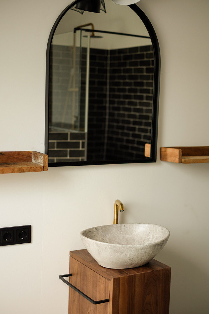 Badezimmer der Wohnung Steiermark mit Steinwaschbecken und Bogenspiegel