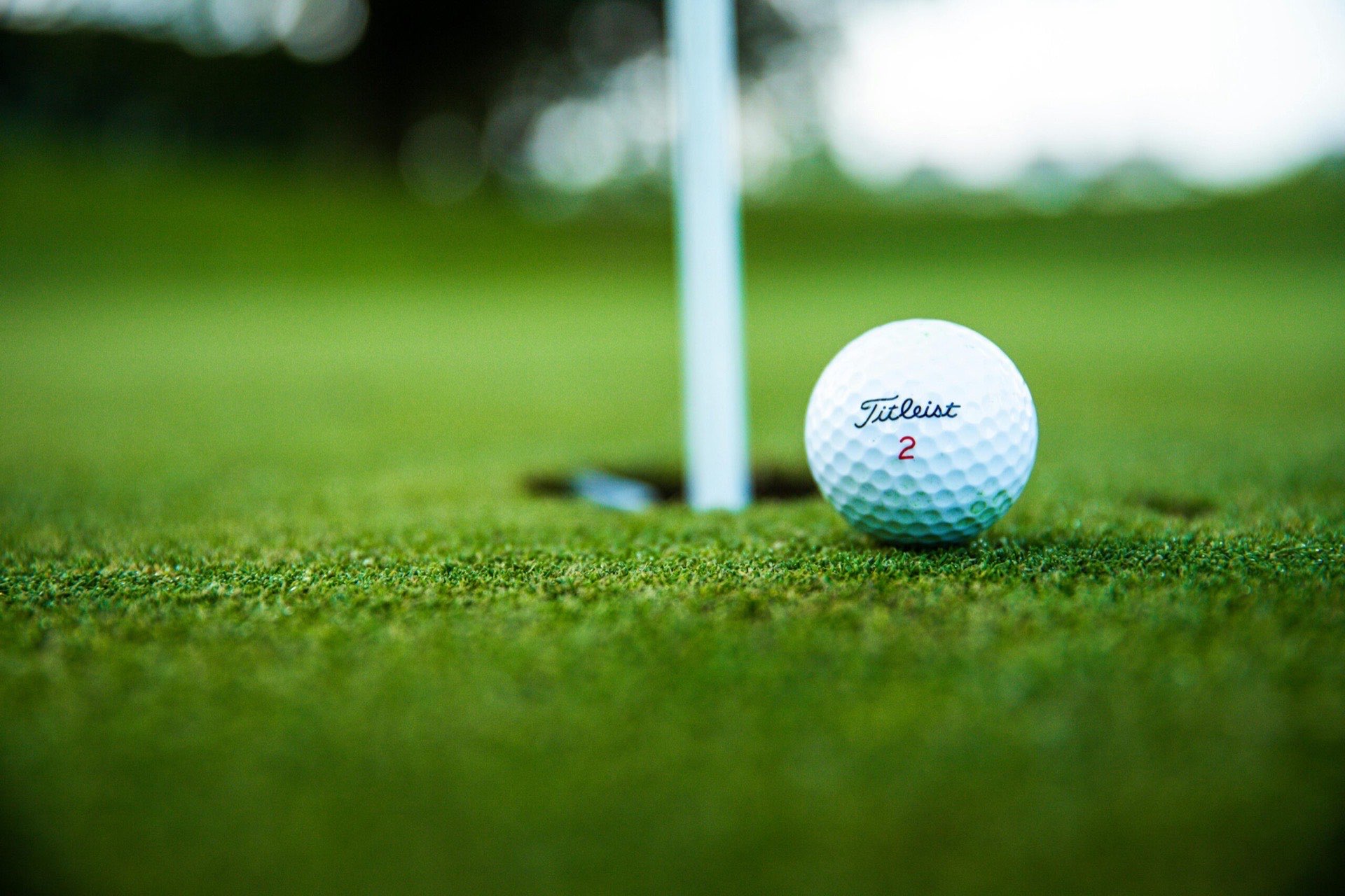Golfball am Rand des Lochs neben der Fahnenstange